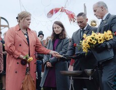 Fünf Personen stehen beim Begräbnis am Grab