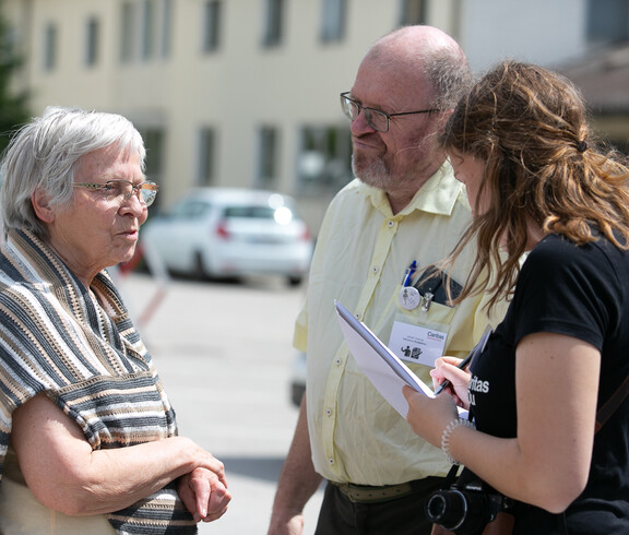 Zwei Frauen und ein Mann stehen im Freien und führen ein Interview