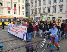 Demonstrationszug beim Feministischen Kampftag 2026 mit einem großen Banner im Vordergrund. Im Hintergrund Häuser am Linzer Hauptplatz.