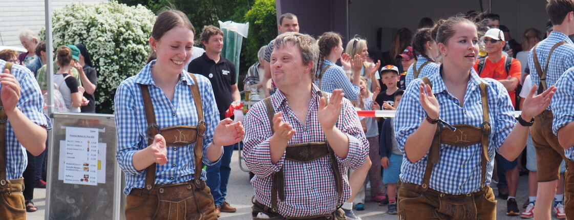 Zwei Männer und eine Frau tanzen in der Lederhosen