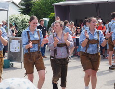 Zwei Männer und eine Frau tanzen in der Lederhosen