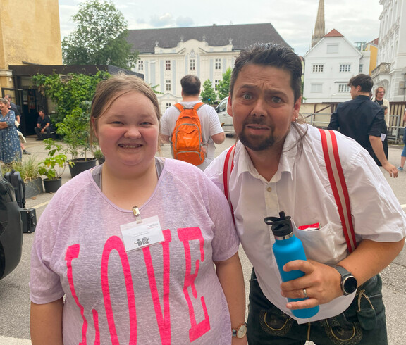Ein Mann und eine Frau stehen nebeneinander und lachen in die Kamera. 
