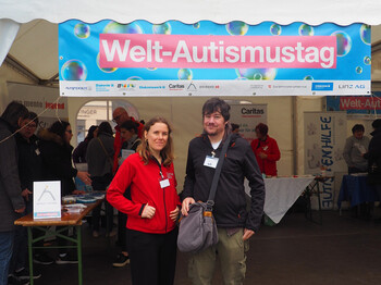 Zwei Personen stehen vor einem Pagodenzelt vor einem Banner. 