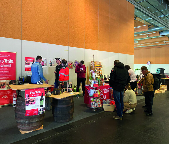 Mehrere Personen stehen auf einen Messestand und infomieren sich. 