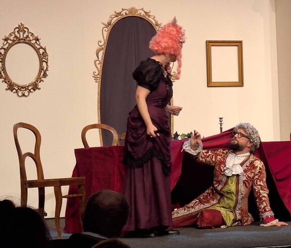 Mann in Kostüm sitzt vor einer Frau auf dem Boden