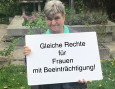 Ein Frau hält ein Schild in der Hand auf dem steht "Gleiche Rechte für Frauen mit Beeinträchtigung"