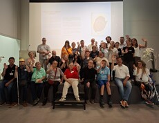 Eine Gruppe von Menschen sitzt für ein Gruppenbild posierend vor einer Leinwand