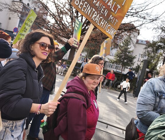 Zwei Demonstrantinnen tragen beim Feministischen Kampftag 2026 in Linz ein Schild, auf dem steht: Stoppt Gewalt an Frauen mit Beeinträchtigung"