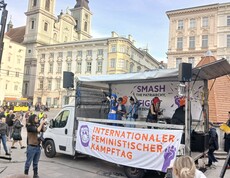 Ein offener Wagen mit einem großen Banner zum Internationalen Feministischen Kampftag am Hauptplaz in Linz. 