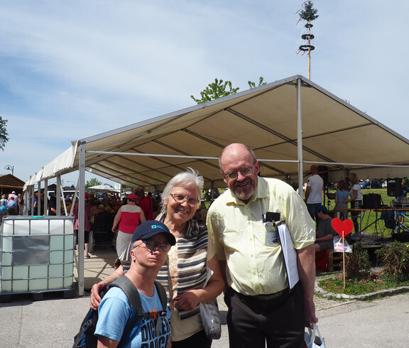 Zwei Frauen und ein Mann stehen vor einem Festzelt