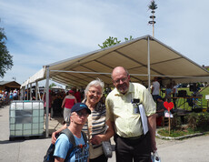 Zwei Frauen und ein Mann stehen vor einem Festzelt